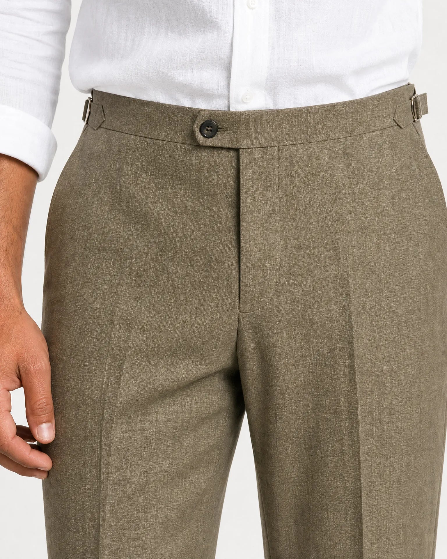 Detailaufnahme der olivgrünen Leinenhose mit seitlichen Verstellern, hohem Bund und feiner Leinenstruktur.