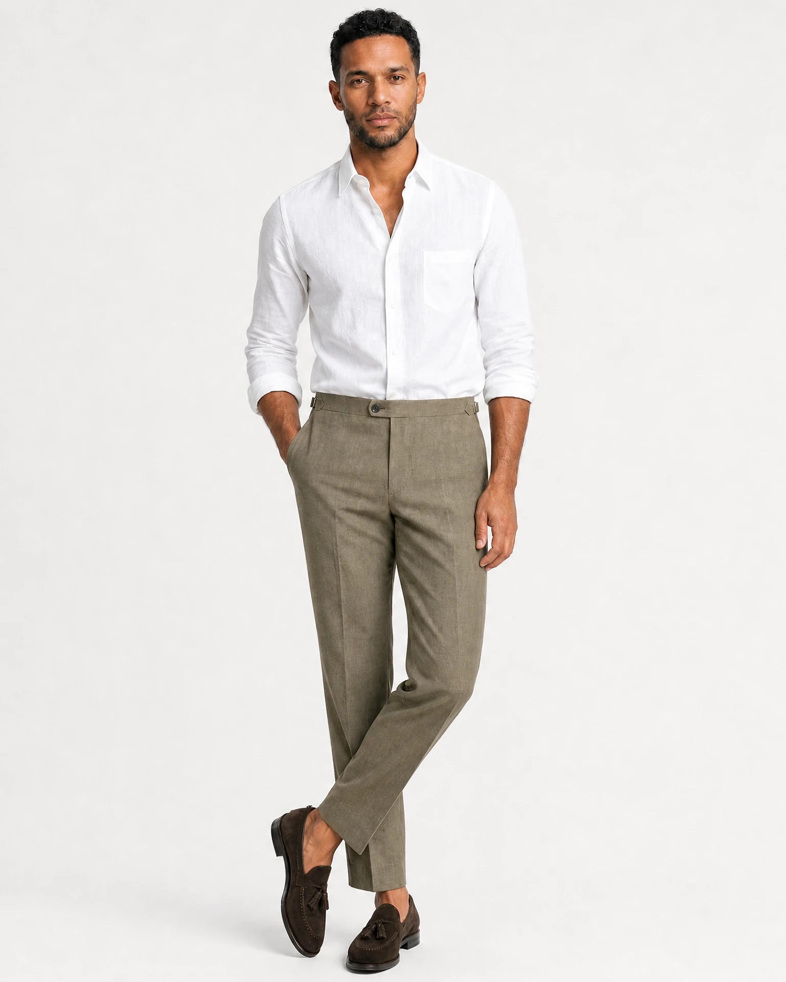 Ganzkörperansicht eines Models in olivgrüner Leinenhose mit leicht überkreuzter Beinhaltung, weißem Hemd und dunkelbraunen Tassel-Loafern.