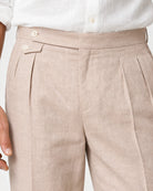 Detailaufnahme der puderfarbenen Leinenhose mit hohem Bund, seitlichem Doppelknopfverschluss und hochwertiger Stoffstruktur von Loro Piana.