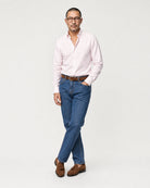Herren Oxford-Hemd in Rosa-Weiß gestreift kombiniert mit blauer Jeans, braunem Gürtel und braunen Loafern.