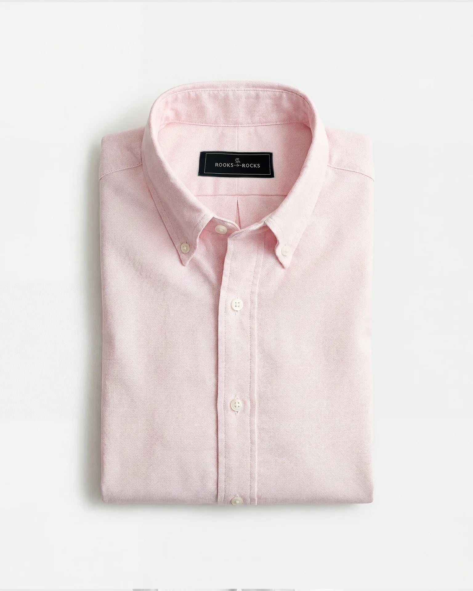 Gefaltetes Rooks & Rocks Oxford-Hemd in Rosé mit Button-Down-Kragen auf hellem Hintergrund