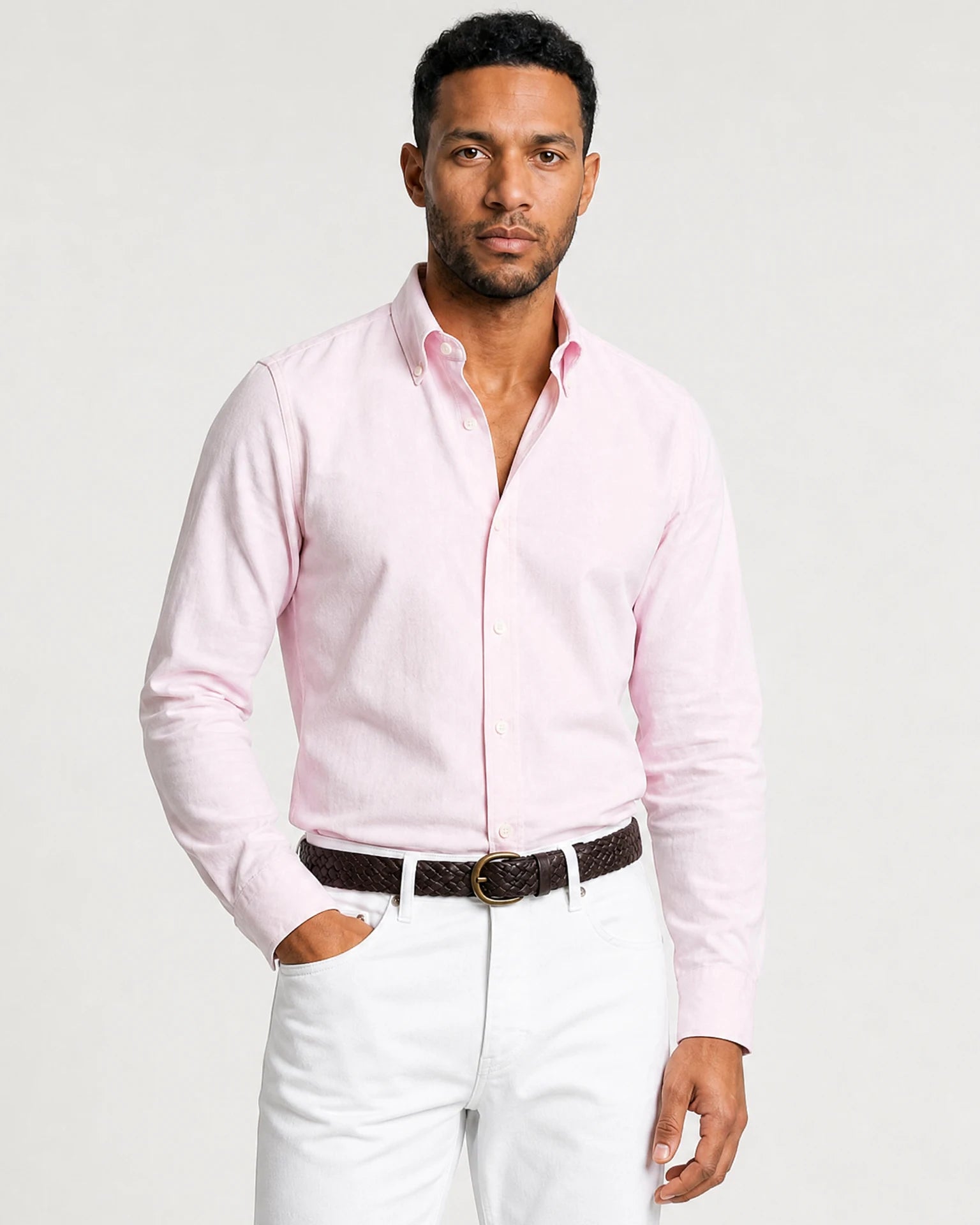 Ganzkörperansicht eines Models mit roséfarbenem Oxford-Hemd, weißer Hose und braunen Loafern.