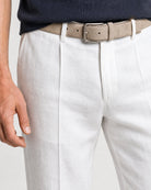 Detailaufnahme der weißen Leinenhose mit Bundfalte, beigem Gürtel und strukturierter Leinenoberfläche.