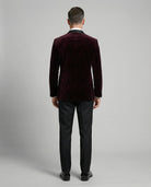 Mann im bordeauxfarbenen Samtsakko mit schwarzer Hose von hinten abgebildet