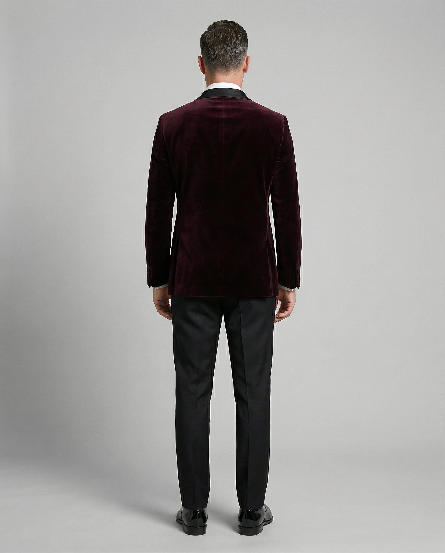 Mann im bordeauxfarbenen Samtsakko mit schwarzer Hose von hinten abgebildet
