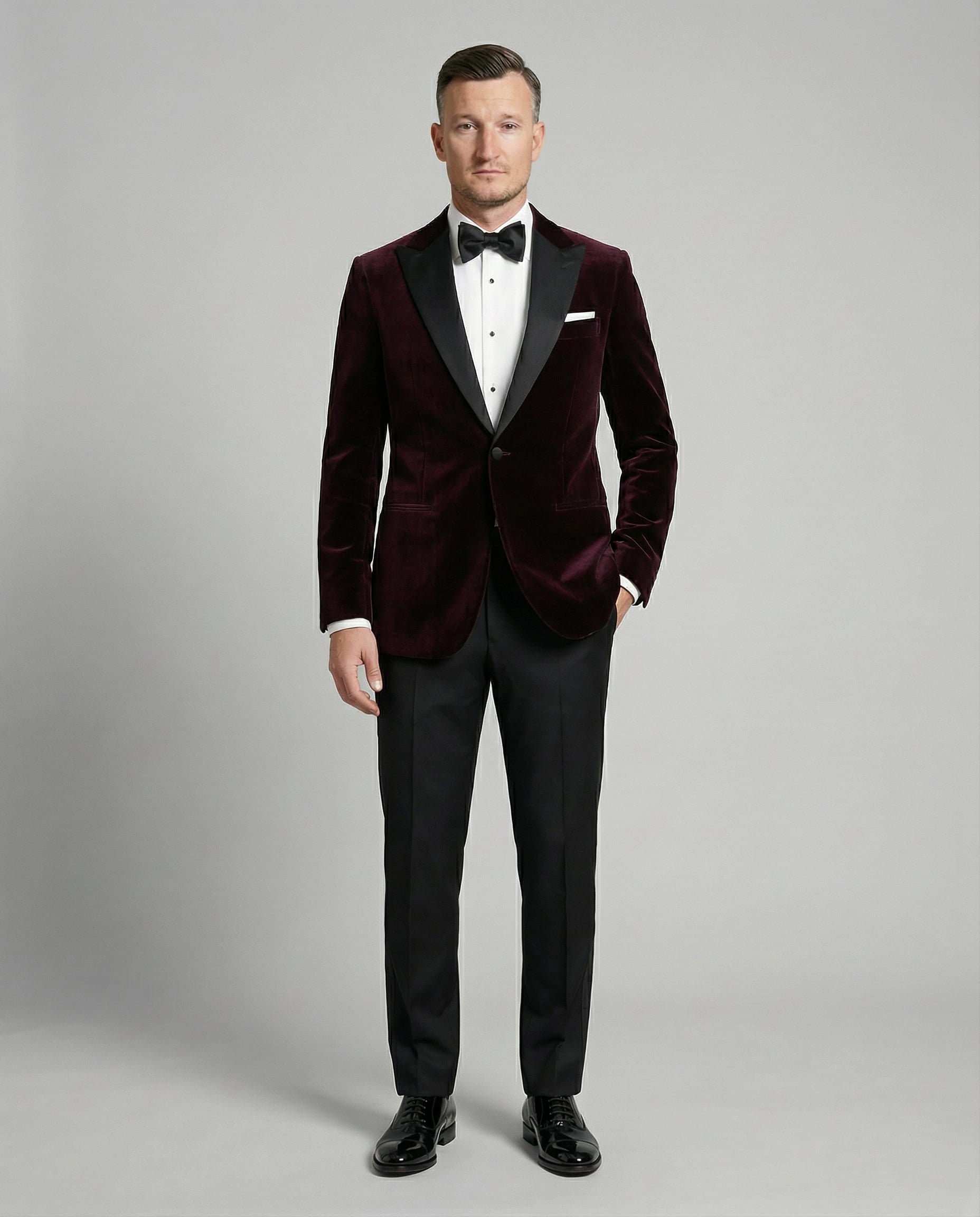 Mann im bordeauxfarbenen Samtsakko mit schwarzer Hose von vorne abgebildet mit Hand in der Tasche