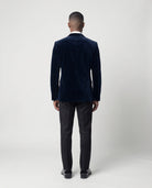 Mann im dunkelblauen Samtsakko mit schwarzer Hose von hinten gezeigt