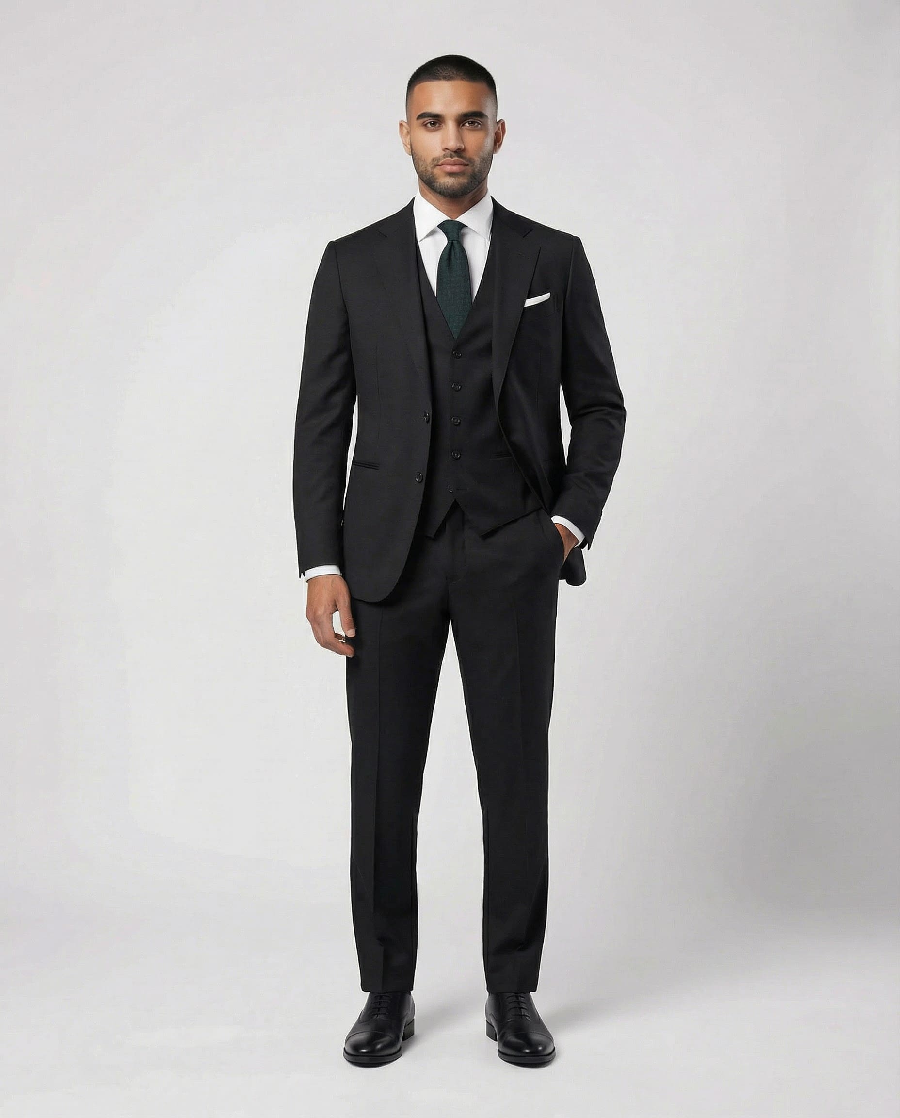 Mann im schwarzen Anzug aus reiner Schurwolle mit Weste und Hand in der Tasche von vorne abgebildet