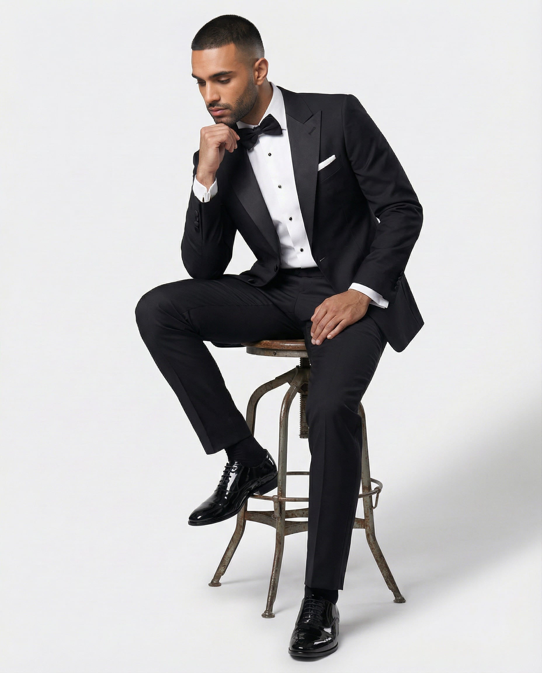 Mann im schwarzen Smoking sitzend auf einem Hocker