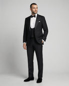 Mann im schwarzen Smoking mit Weste und Hand in der Tasche von vorne abgebildet