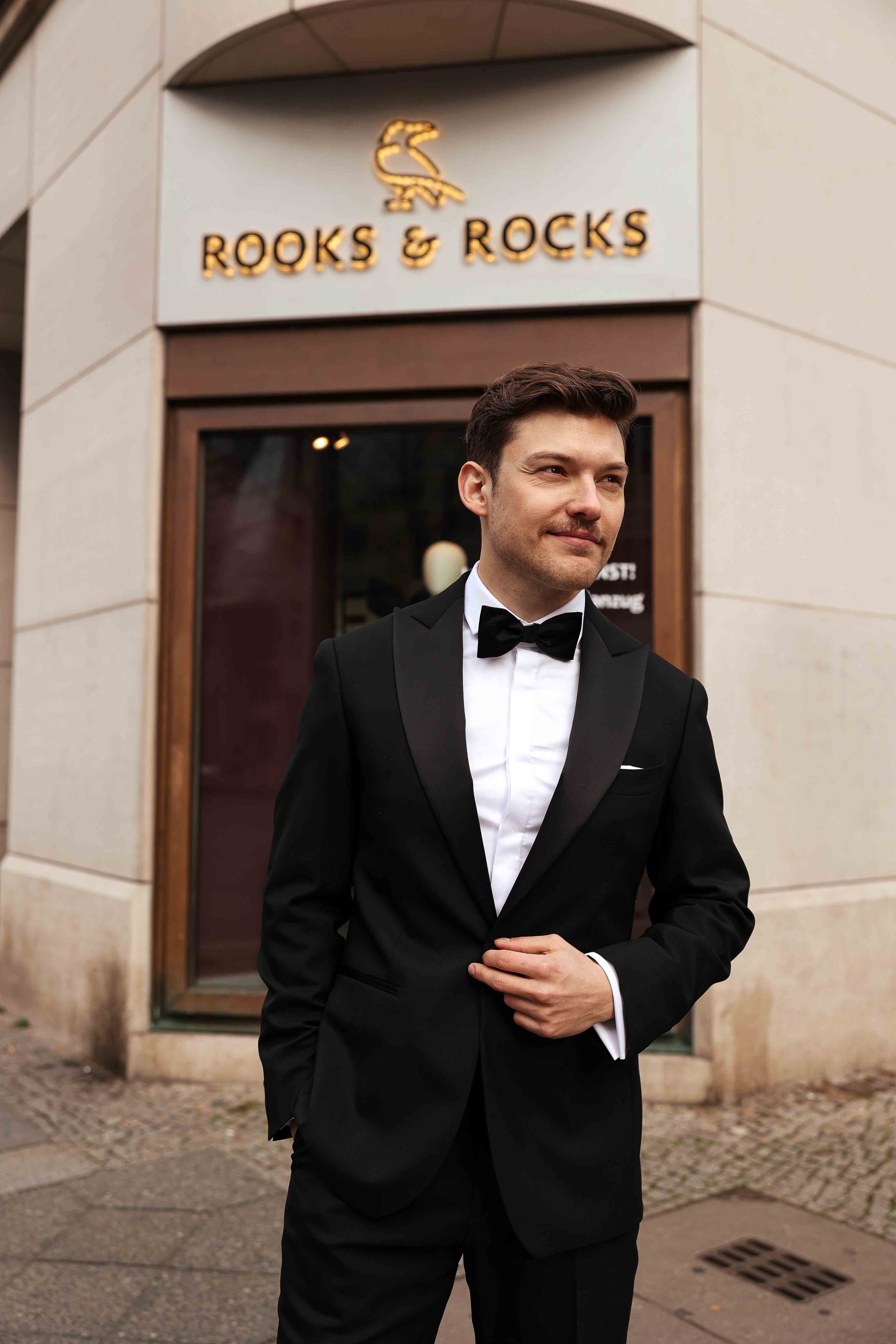 Bräutigam steht im Smoking vor unserer Berliner Rooks & Rocks Filiale