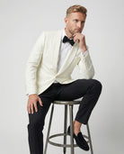 Mann im weißes Dinnerjacket mit schwarzer Hose auf einem Hocker sitzen